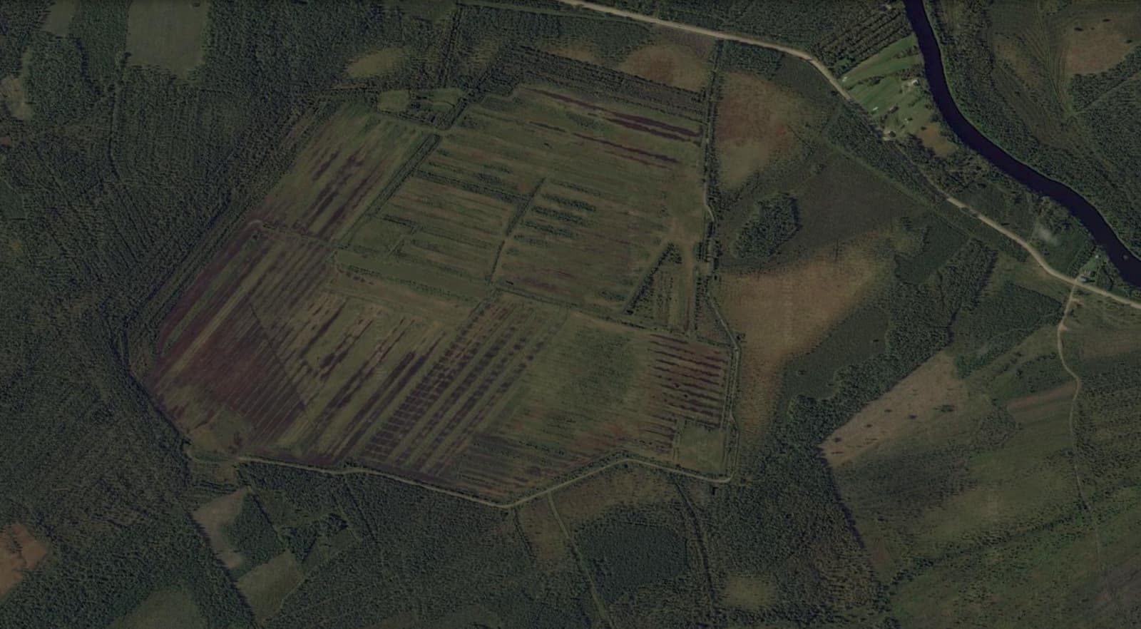 A satellite view of a farm showcasing a vast, expansive field surrounded by greenery and agricultural structures.