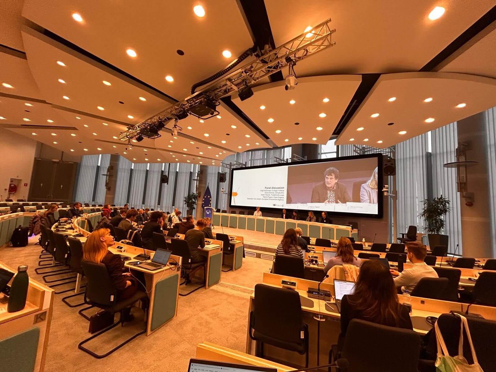 A large conference room filled with people seated at tables, engaged in discussion and collaboration.